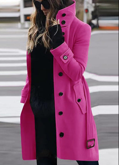 Person wearing a bright pink coat with black buttons on a blurred street background