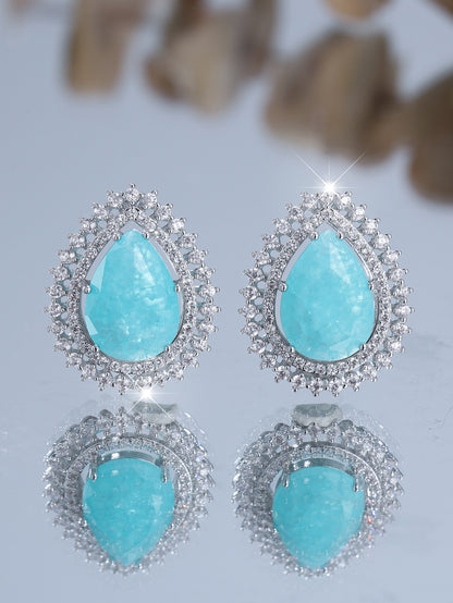 Turquoise teardrop earrings with silver accents on a light gray background