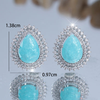 Turquoise teardrop earrings with silver accents on a light gray background