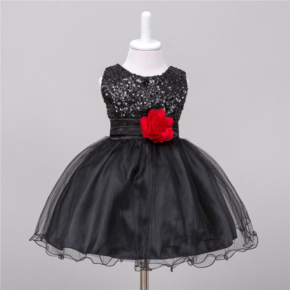 Black sequin dress with a red flower on a mannequin against a gray background