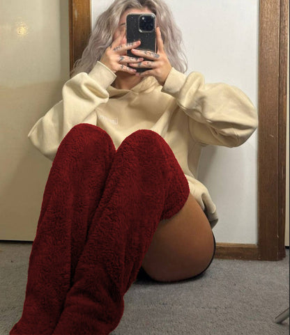 beautiful woman wearing a beige sweatshirt and red pants sitting on the floor in front of a mirror