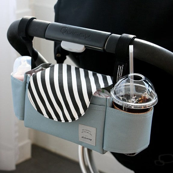 Stroller organizer with cup holder and striped pouch attached to a stroller handle.