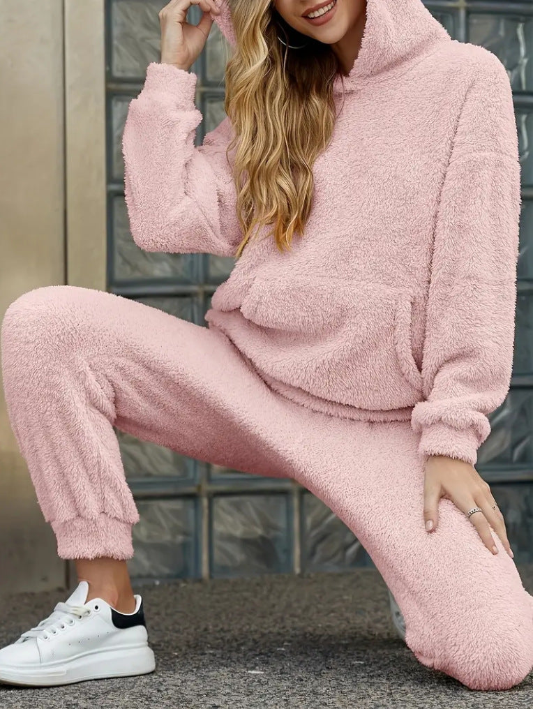 Person wearing a pink fleece tracksuit with white sneakers.